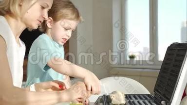 年轻的女人在厨房做华夫饼，可爱的男孩帮助她。 一大早就不规律地做早餐