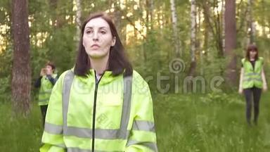 女志愿者穿着绿色背心，在树林里搜寻失踪的人大声叫着