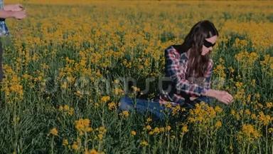 男孩送给<strong>妈妈</strong>一束野花，亲吻她坐在黄花丛中的草地..