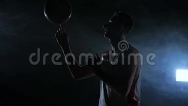 近镜头篮球运动员旋转球在他的<strong>手指</strong>，黑暗的雾室与泛光<strong>灯</strong>