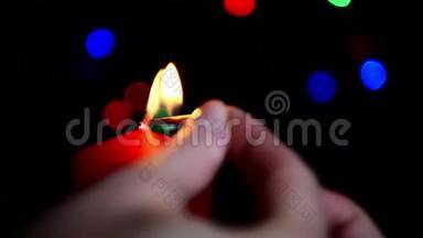 女孩在博克的背景上点燃了一支<strong>大红</strong>蜡烛。 点燃蜡烛的特写。