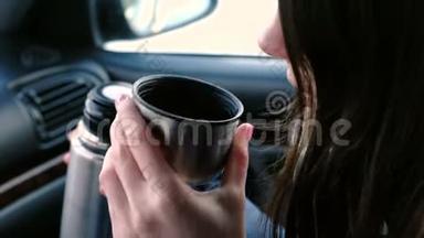 特写镜头：一个面目全非的女人在冬天坐在车里的热水瓶里喝着一杯热茶。