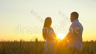 浪漫的年轻幸福夫妇在夕阳下金色麦田的<strong>剪影</strong>。 女人和男人拥抱<strong>亲吻</strong>