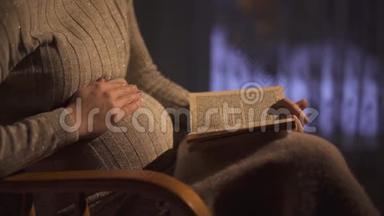 孕妇晚上坐在黑暗的房间里的摇椅上看书。