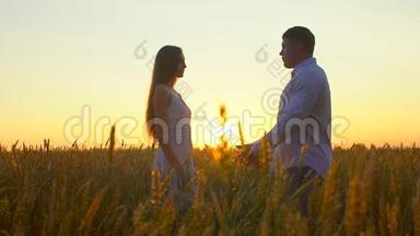 <strong>浪漫</strong>的年轻幸福夫妇在<strong>夕阳</strong>下金色麦田的剪影。 女人和男人拥抱亲吻