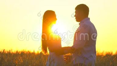 浪漫的年轻幸福夫妇在夕阳下金色麦田的<strong>剪影</strong>。 女<strong>人</strong>和男<strong>人</strong>拥抱亲吻