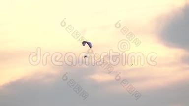 不知名的动力滑翔伞在日落的天空中飞得很高