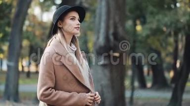 <strong>迷人</strong>的女孩在<strong>浪漫</strong>的外观，带着黑色帽子走在公园的小巷，看着相机，给了惊人的。