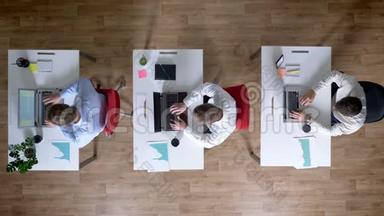 三个年轻的商人正在使用笔记本电脑，同时离开工作场所，工作观念，办公室观念