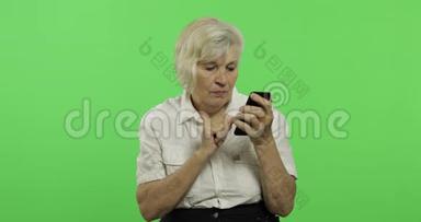 一位老年妇女在智能手机上工作。 <strong>老奶奶</strong>笑了。 铬键