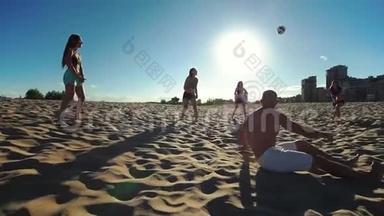 一群年轻的运动员打沙滩排球，其中一名运动员在秋天从沙滩上站起来