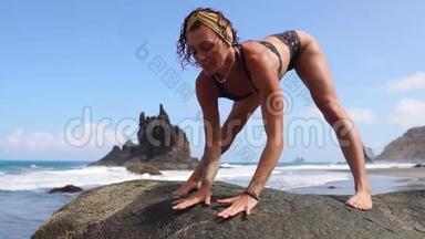 女子在靠近水面的海面上背着海浪做体操. 瑜伽练习。 健康的生活方式。 女人在做什么