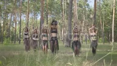 一群女舞者，化妆，穿着神秘的华丽服装，在大自然中翩翩起舞。 森林精灵