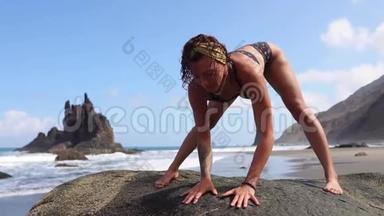 一位在海洋上从事体操的妇女坐在绳子上，在水面附近的一座桥上背着海浪，