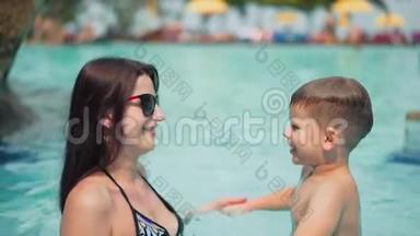 暑假期间，美丽的妈妈和她的儿子一起在游泳池里嬉笑玩耍
