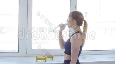 健身理念。 年轻女子在白色<strong>室内运动</strong>后饮用水
