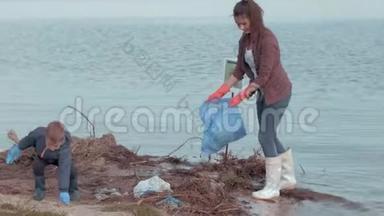停止污染，女志愿者带着小男孩从河边的塑料垃圾中清理肮脏的海岸