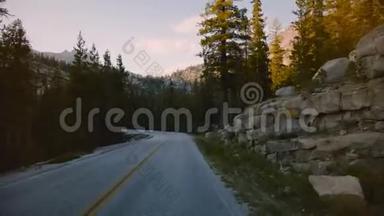 汽车中的POV摄像机沿着美丽的森林山路在日落的岩石之间移动，在约塞米蒂公园缓慢的运动。