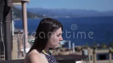 一个年轻的女孩很早就站在阳台上俯瞰<strong>大海</strong>，喝着咖啡。 <strong>大海</strong>，休息，早晨