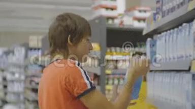 超市里的<strong>青少年</strong>。 白人<strong>青少年</strong>穿红色t恤选择长寿牛奶在商店货架背景。