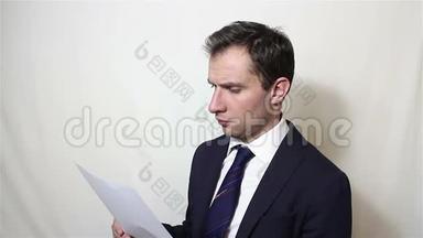 一位年轻英俊的商人拿起一张纸和一份合同，仔细阅读。