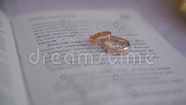 两枚金色结婚戒指躺在书页上，上面写着文字
