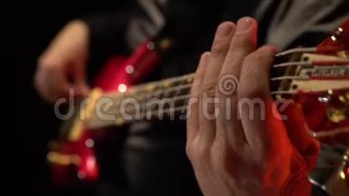 低音吉他。 人们用手指指着音乐家的琴弦。 快关门。 黑色背景