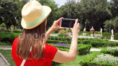 女人用手机慢动作拍公园的照片。 女游客在别墅Borghese拍照
