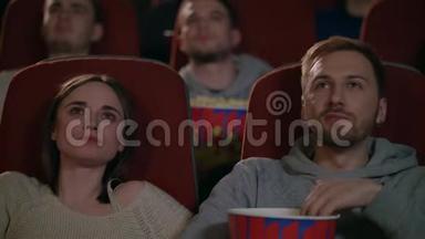 年轻夫妇在电影院欣赏电影。 两个人吃爆米花讨论电影