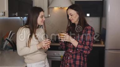两个女朋友在<strong>厨房</strong>喝橙汁，<strong>拿出</strong>眼镜和沟通。