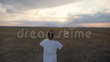 日落时分，一个男孩在田野里跑，扔了一架纸飞机。 幸福孩子的概念