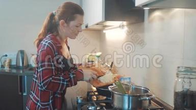 女人妈妈在厨房做饭的概念。 在平底锅里<strong>煮汤</strong>，把洋葱倒进平底锅里，就能烤面包了。 女孩