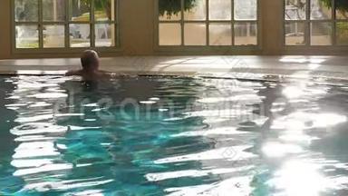 帅哥在蓝水里游泳，在豪华的室内游泳池里休息