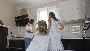 快乐的<strong>小</strong>女孩穿着白色连衣裙和<strong>姐姐</strong>和妈妈一起跳舞，一边听音乐，一边在厨房做饭
