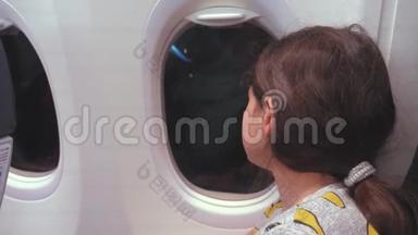 航空飞机概念。 年轻的少女在飞行时看着飞机在夜间的窗口飞行。 年轻乘客