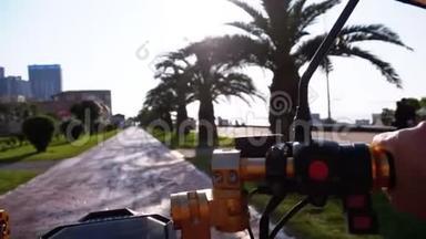 在度假小镇上，POV骑着一辆电动自行车在一条红色<strong>的</strong>自行车道上骑着棕榈树