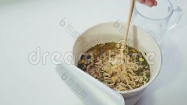 有人把方便面和热水和筷子混合在纸碗里。