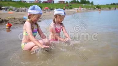 两个小女孩在海滩上倒水。 <strong>幼儿</strong>玩，笑，创编泼水.. 海上<strong>暑假</strong>..
