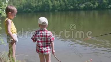 两个孩子站在河岸上。 在儿童棒的手中.. 夏日炎炎。