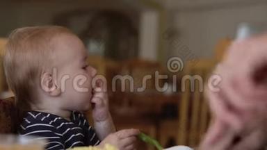 小<strong>可爱</strong>的<strong>宝宝</strong>坐在婴儿椅上<strong>吃</strong>食物。
