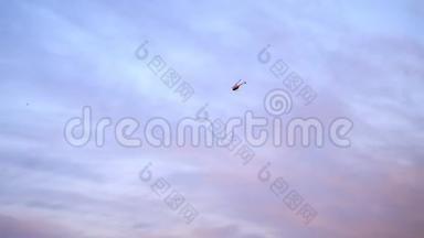 蓝天、云彩和粉红色的日落，一架红色的直升机在天空中飞翔