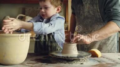 可爱的孩子正和<strong>老爷爷</strong>一起在传统的作坊里学习陶器。 他把手弄湿，形成