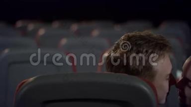 可爱的一对情侣在电影院的后座上缓慢地接吻。
