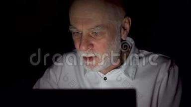 老人在家休息，深夜用笔记本电脑阅读新闻。 只有一张漆黑的脸