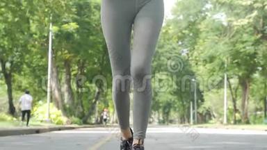 年轻迷人的女人在绿色城市公园跑步锻炼户外健身跟踪可穿戴技术。