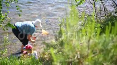 祖母和孙子钓鱼网。 山区河流的海岸。 夏日炎炎的清凉水