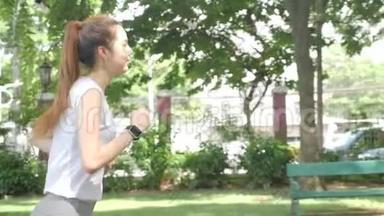 年轻迷人的女人在绿色城市公园跑步锻炼户外健身跟踪可穿戴技术。