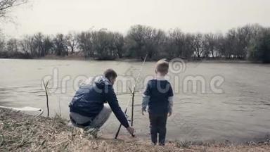 年轻的父亲和小儿子一起在<strong>河边钓鱼</strong>