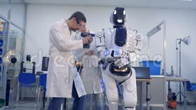 两名技术人员正在用钻头调整一个像人一样的机器人