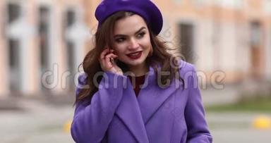 穿紫色外套的时髦女人在街上打电话。